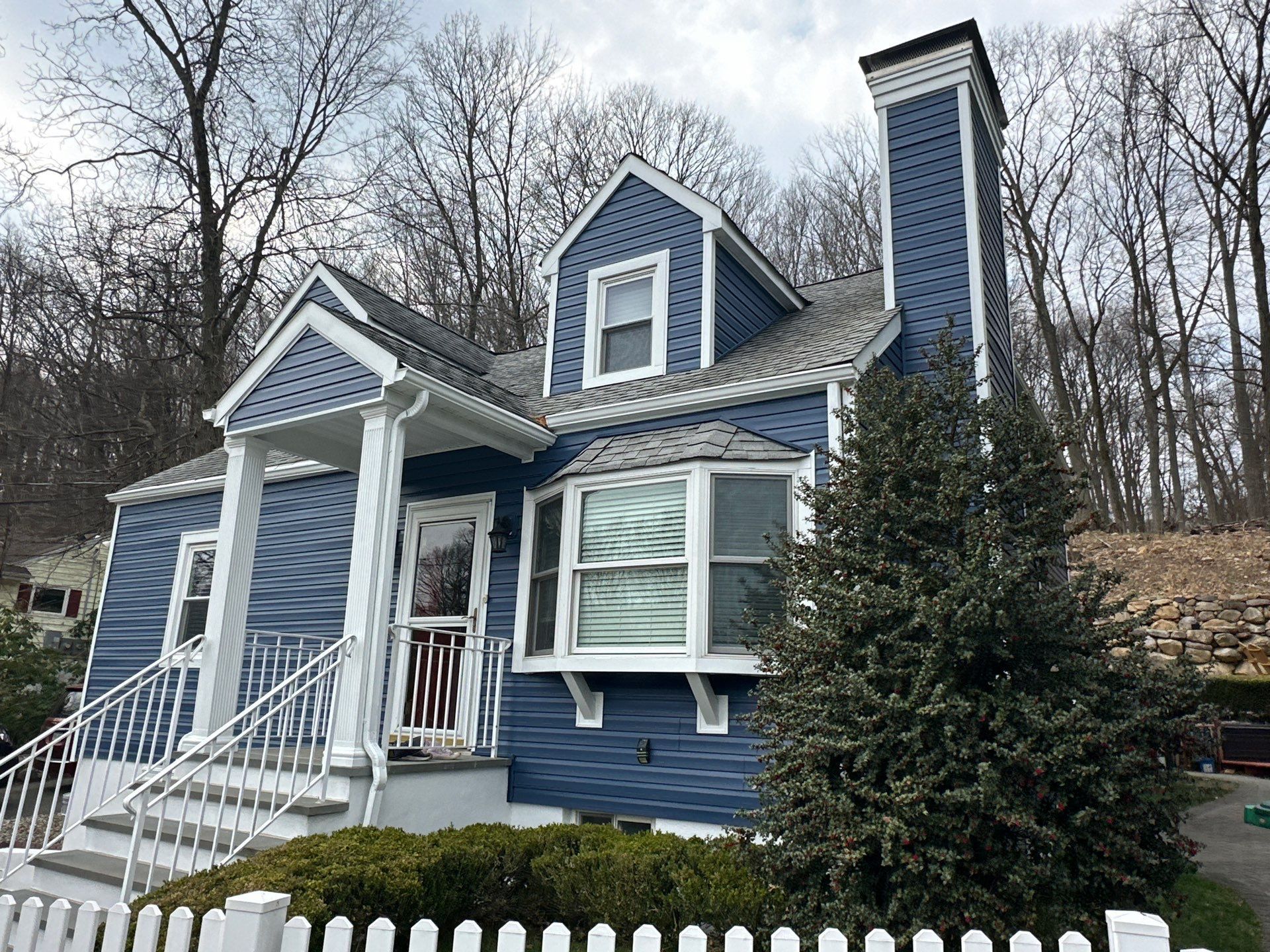 A blue house with white trim and a white picket fence