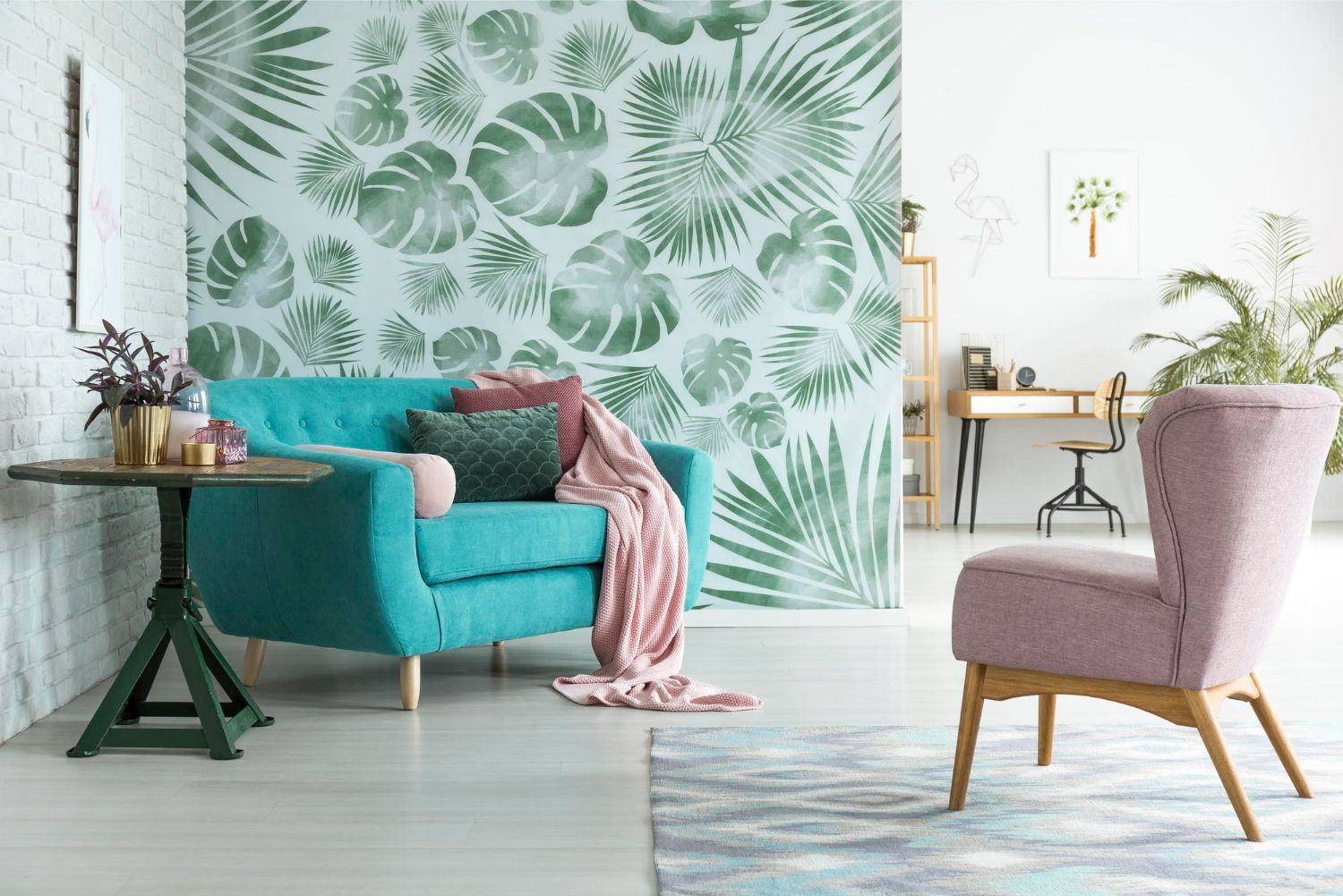 Living room with teal sofa, pink chair, botanical wallpaper, and round table.