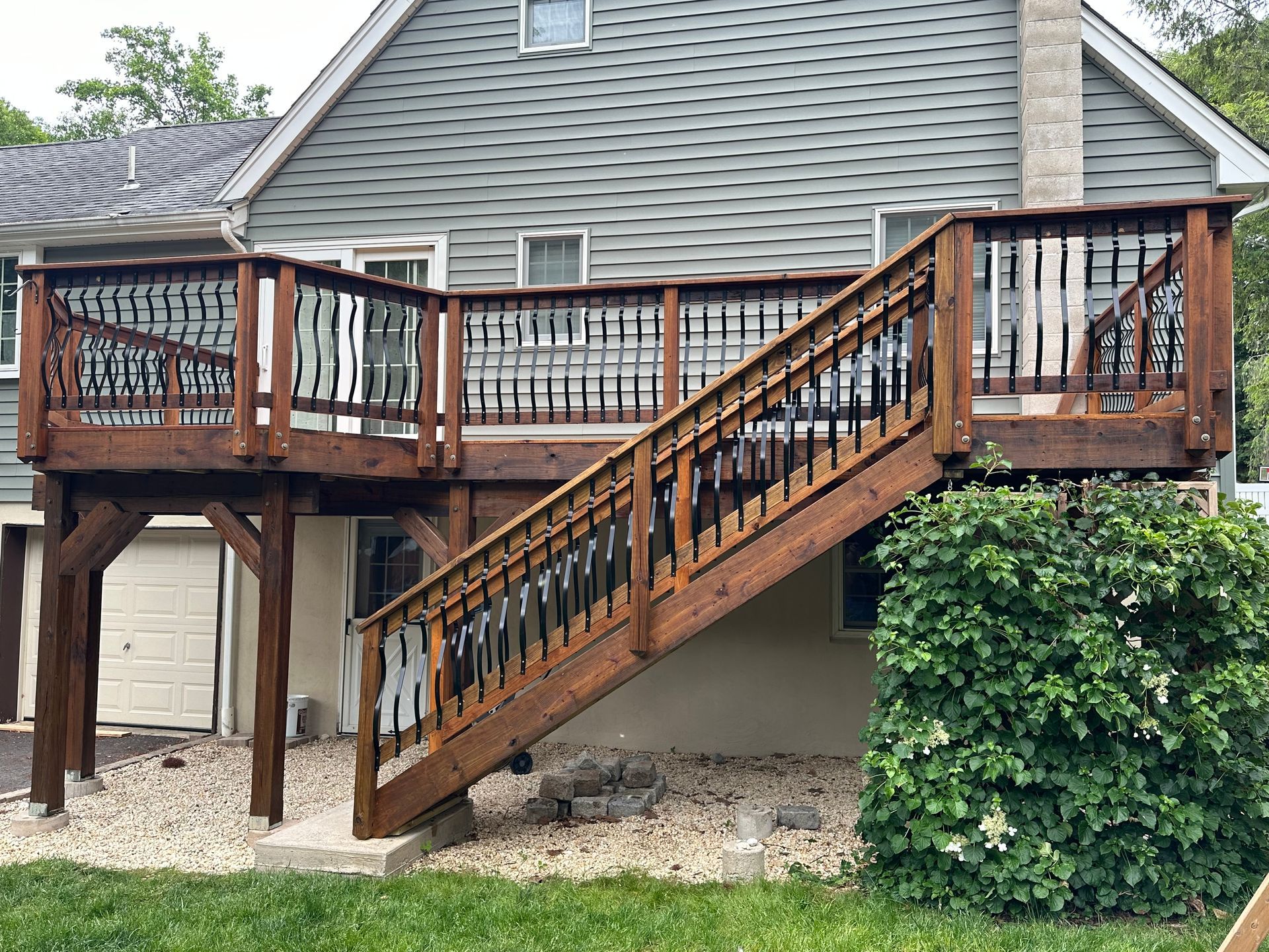 Wooden deck with stairs attached to a two-story house. The deck is stained brown.