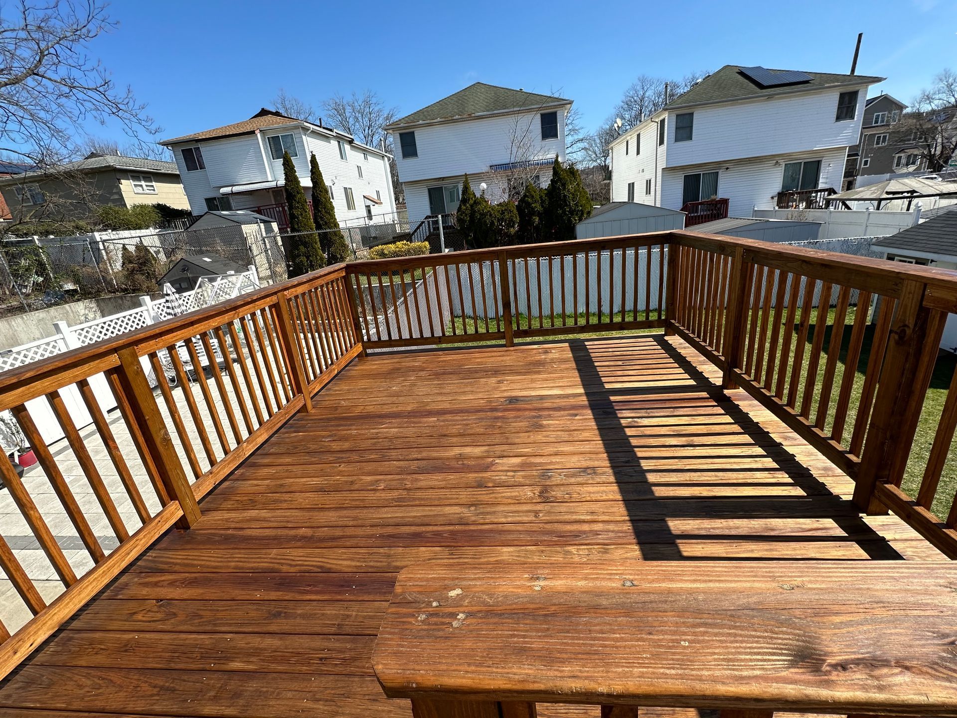 A wooden deck with a railing in front of a house.