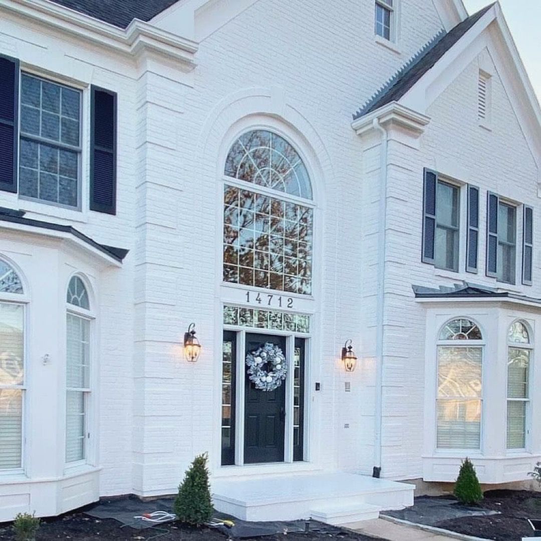 A white house with black shutters and a wreath on the door