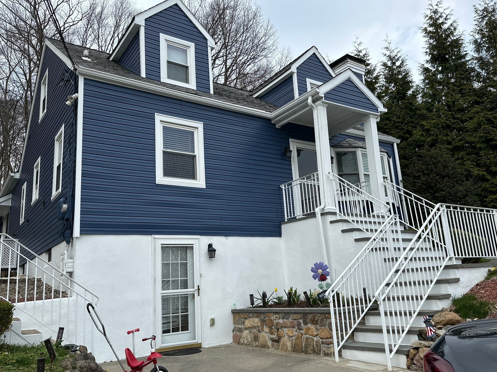 Two-story house with blue siding, white trim, and a white porch with stairs.