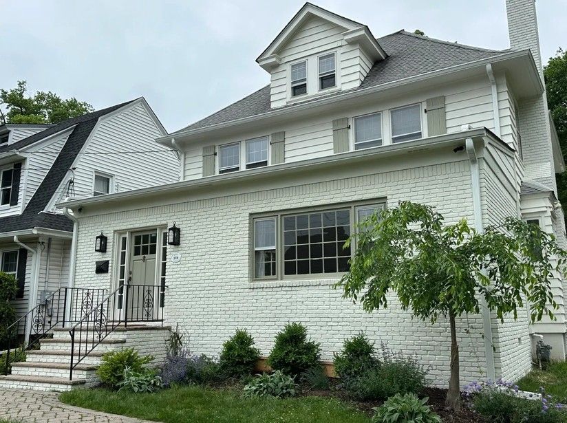 A large white brick house with a lot of windows and trees in front of it.