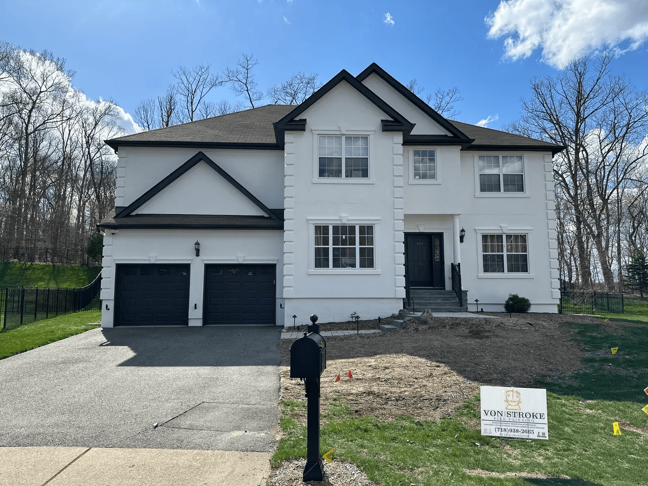 A large white house with black garage doors is for sale.