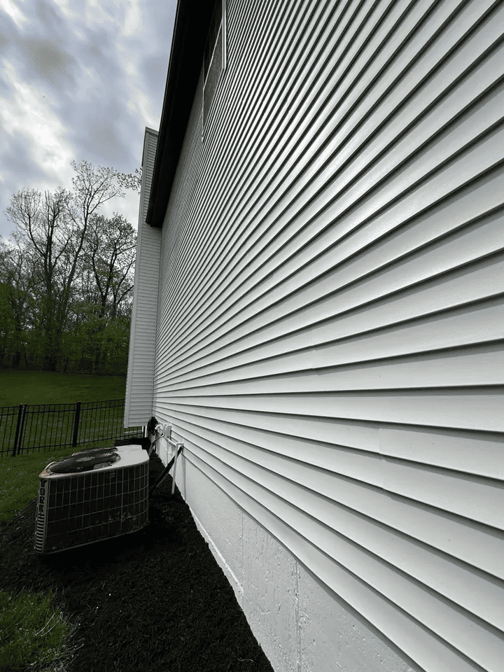 A large white house with a fence and trees in the background.