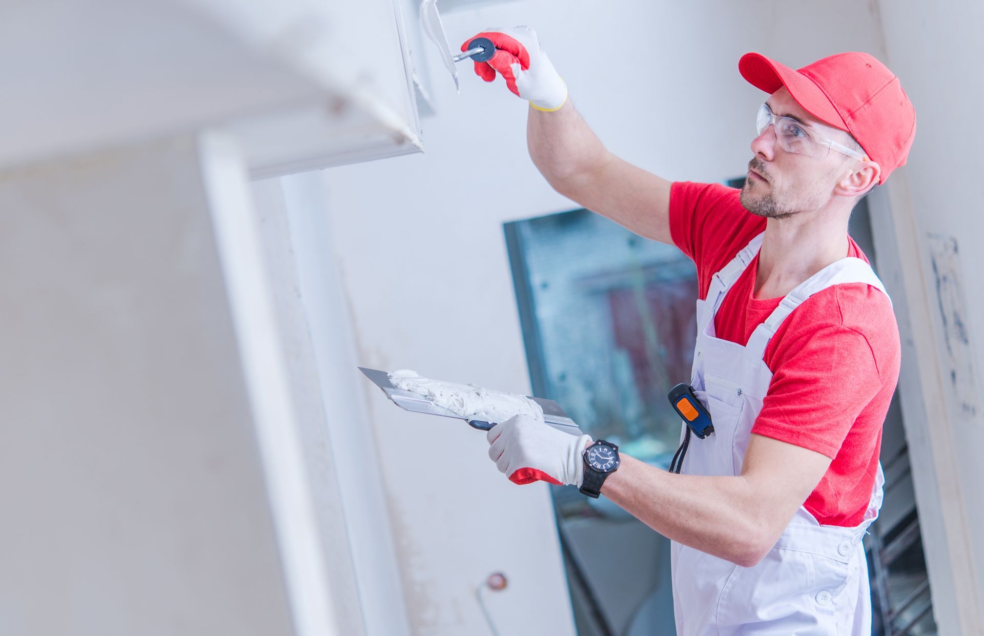 A man is plastering a wall with a spatula.