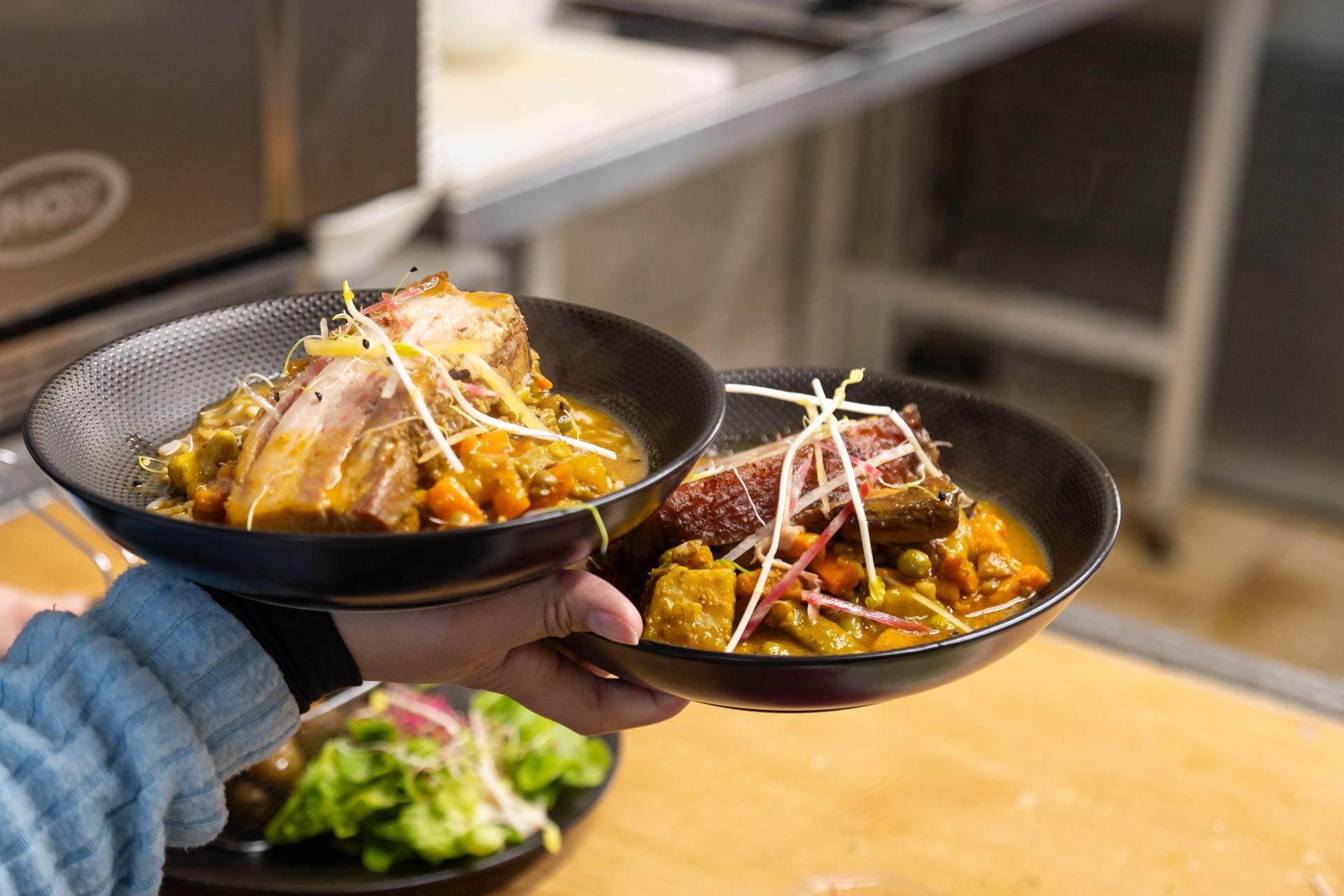 Une personne tient deux bols de nourriture dans ses mains.