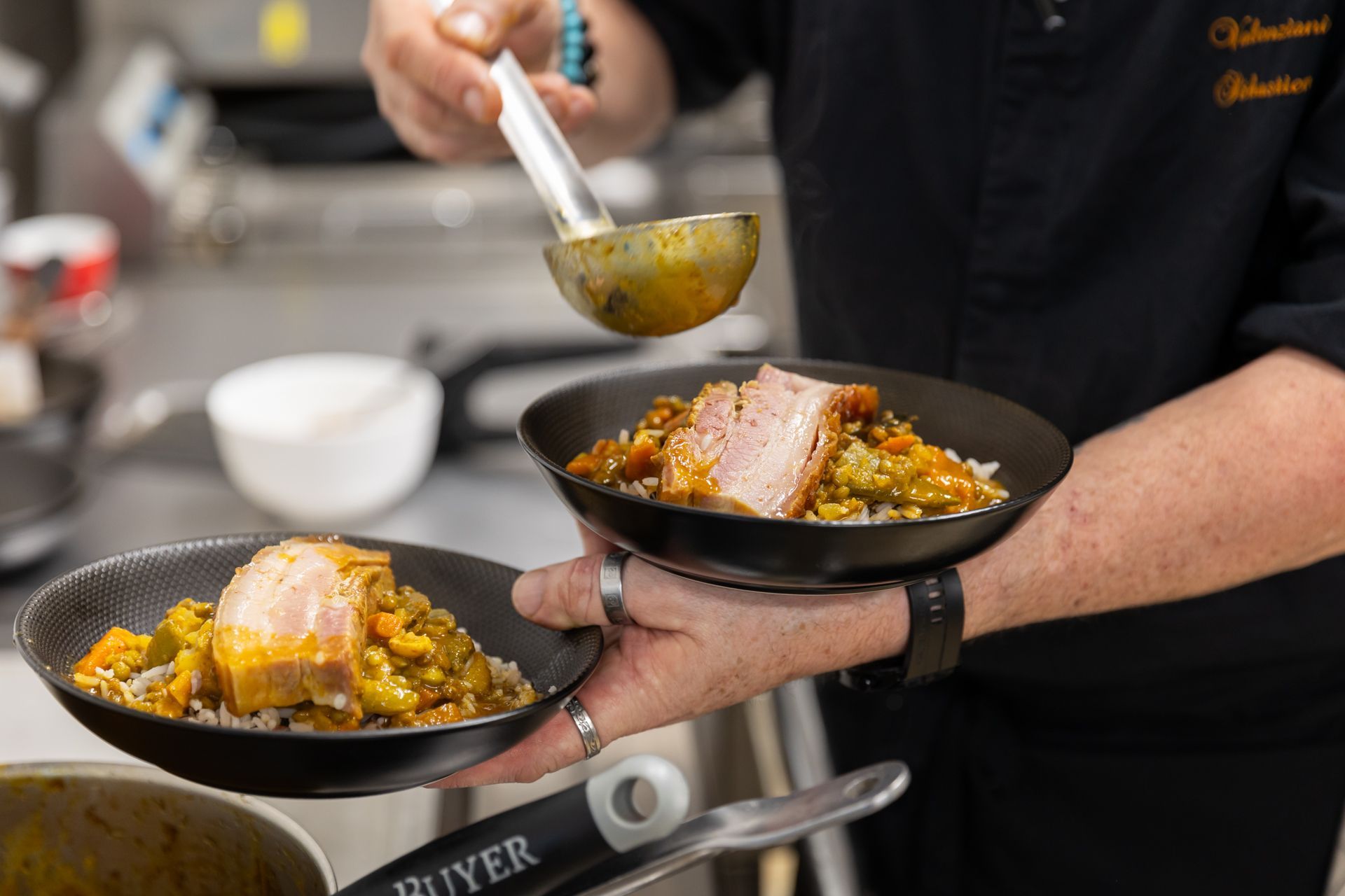 Un chef verse une louche dans un bol de nourriture.