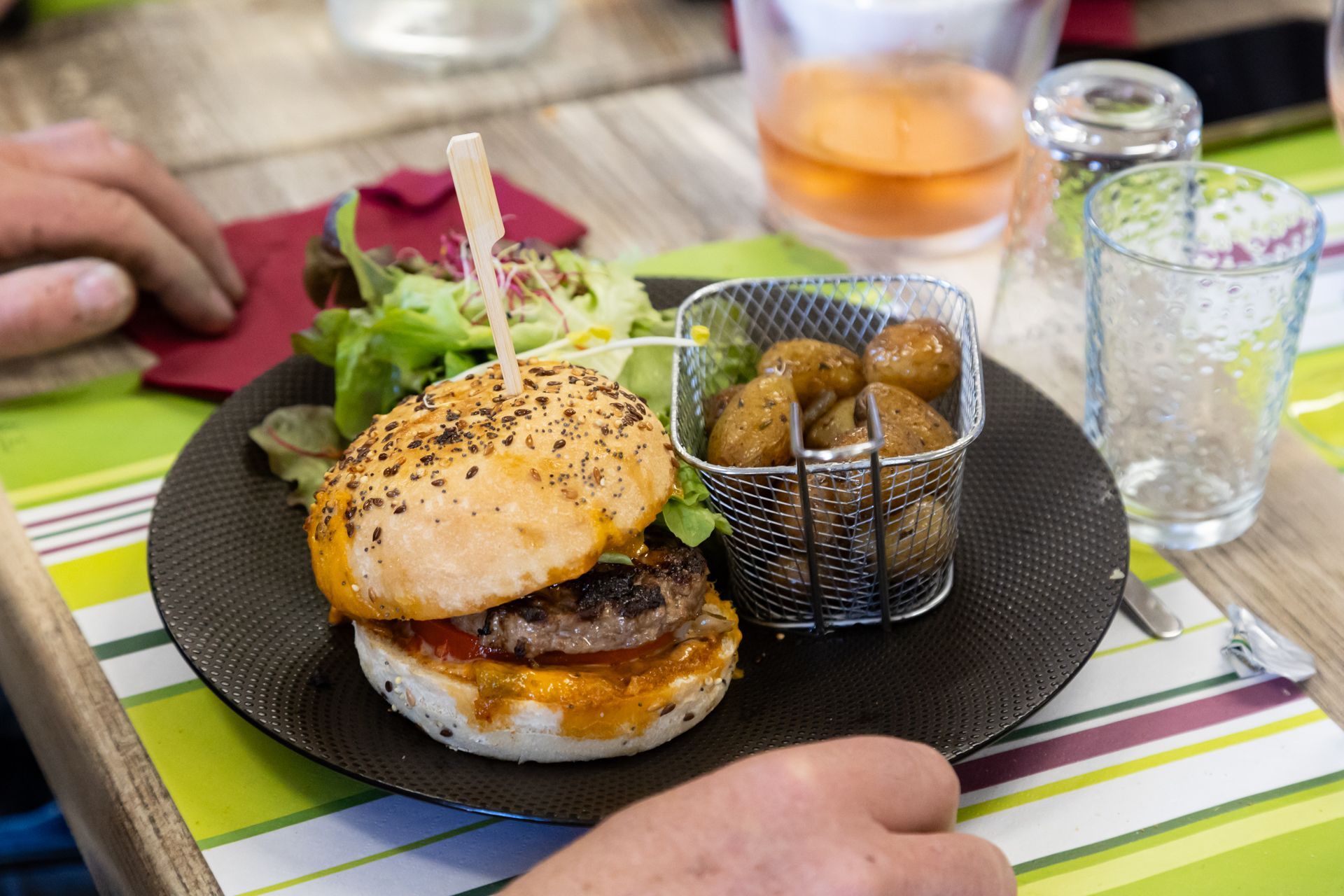 Une personne mange un hamburger et des pommes de terre dans une assiette.