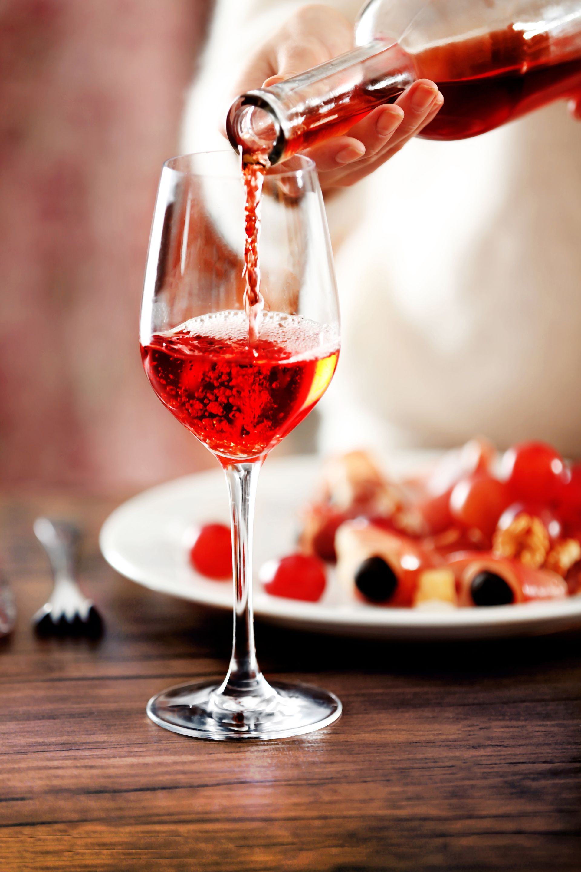 Une personne verse du vin dans un verre posé sur une table.