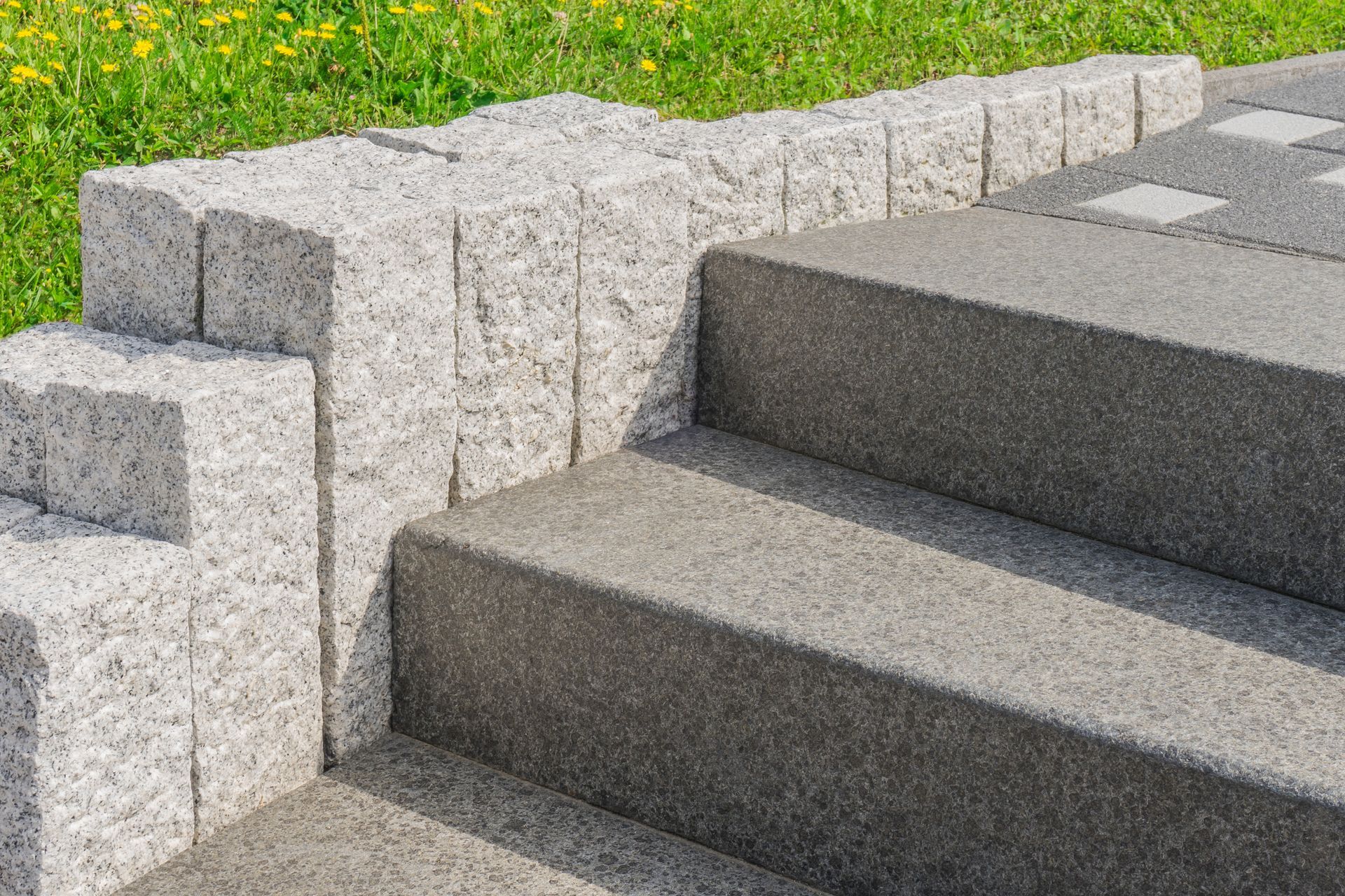 Stone steps and retaining wall, gray and light gray, outdoors with grass.