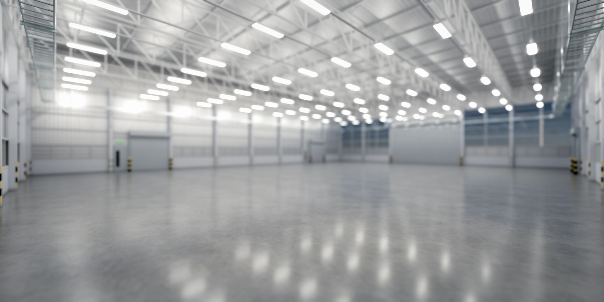 Large, empty warehouse interior with a high ceiling, fluorescent lights, and a polished concrete floor.