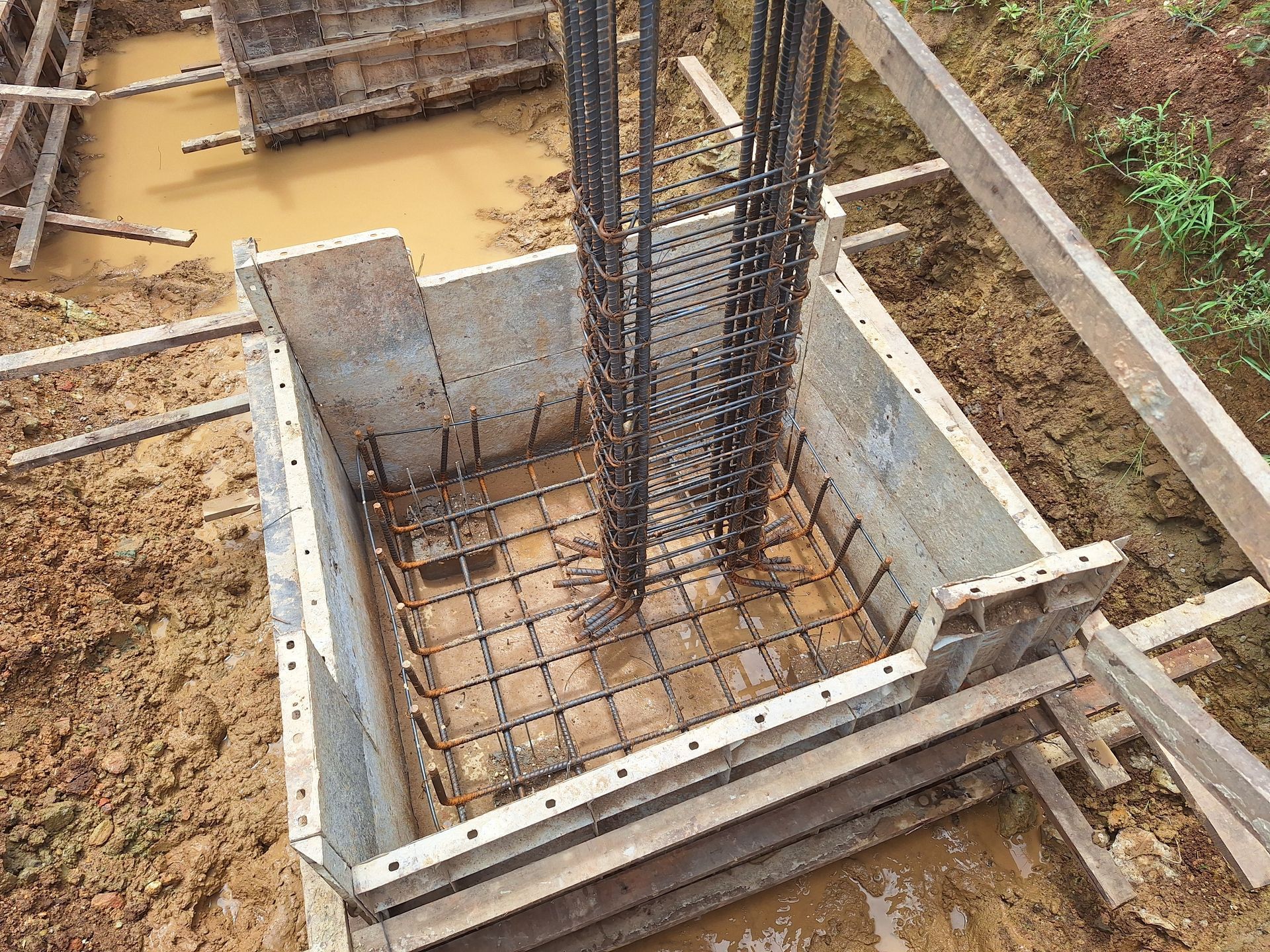 Construction site with a concrete foundation formwork and steel reinforcement.