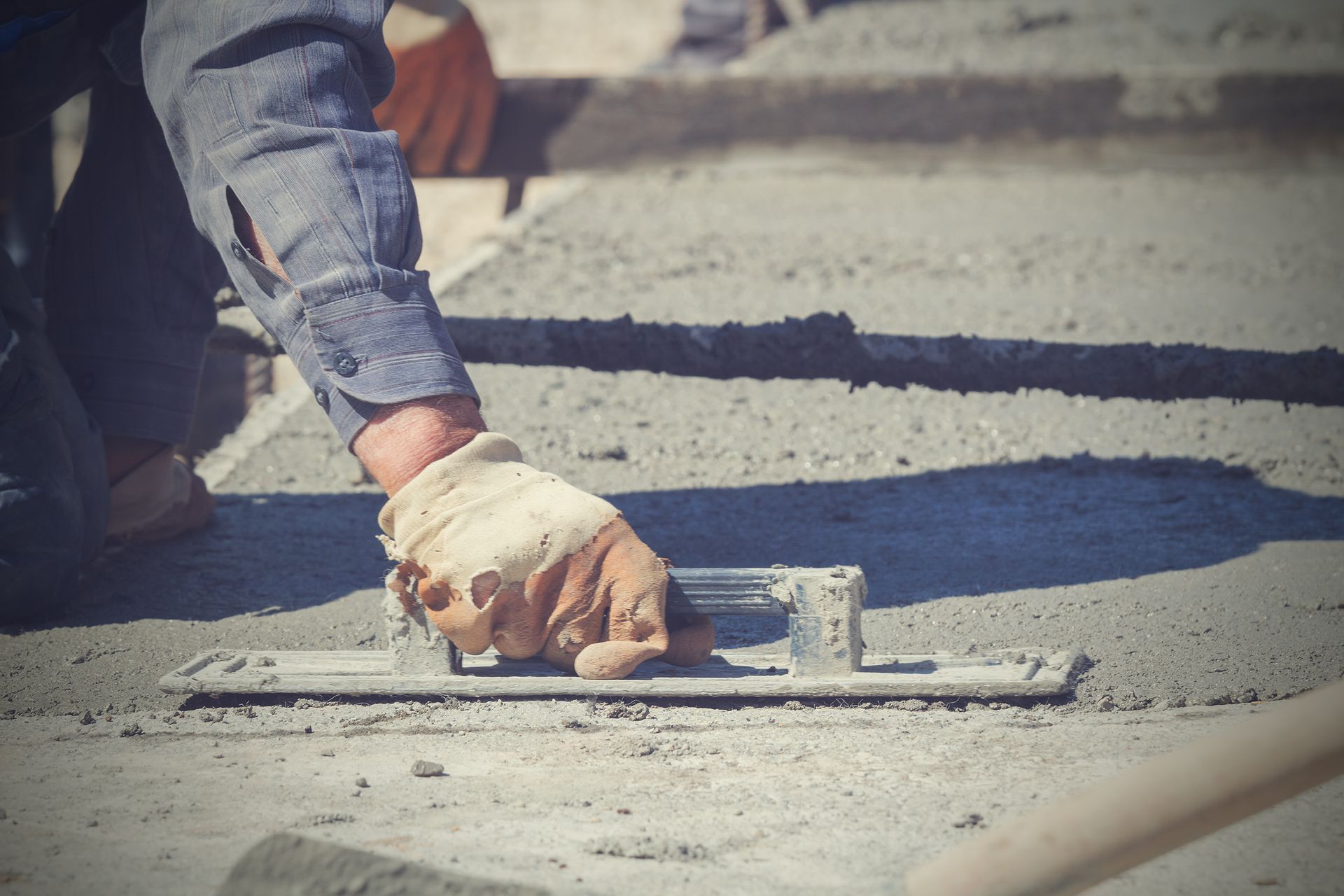 Person smoothing wet concrete with a trowel.