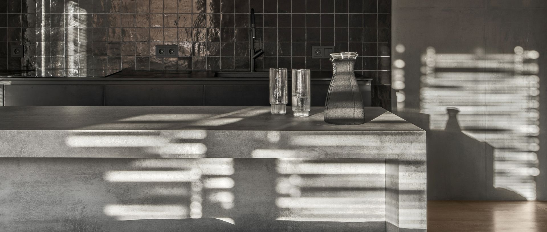 A modern kitchen counter with two glasses and a carafe.