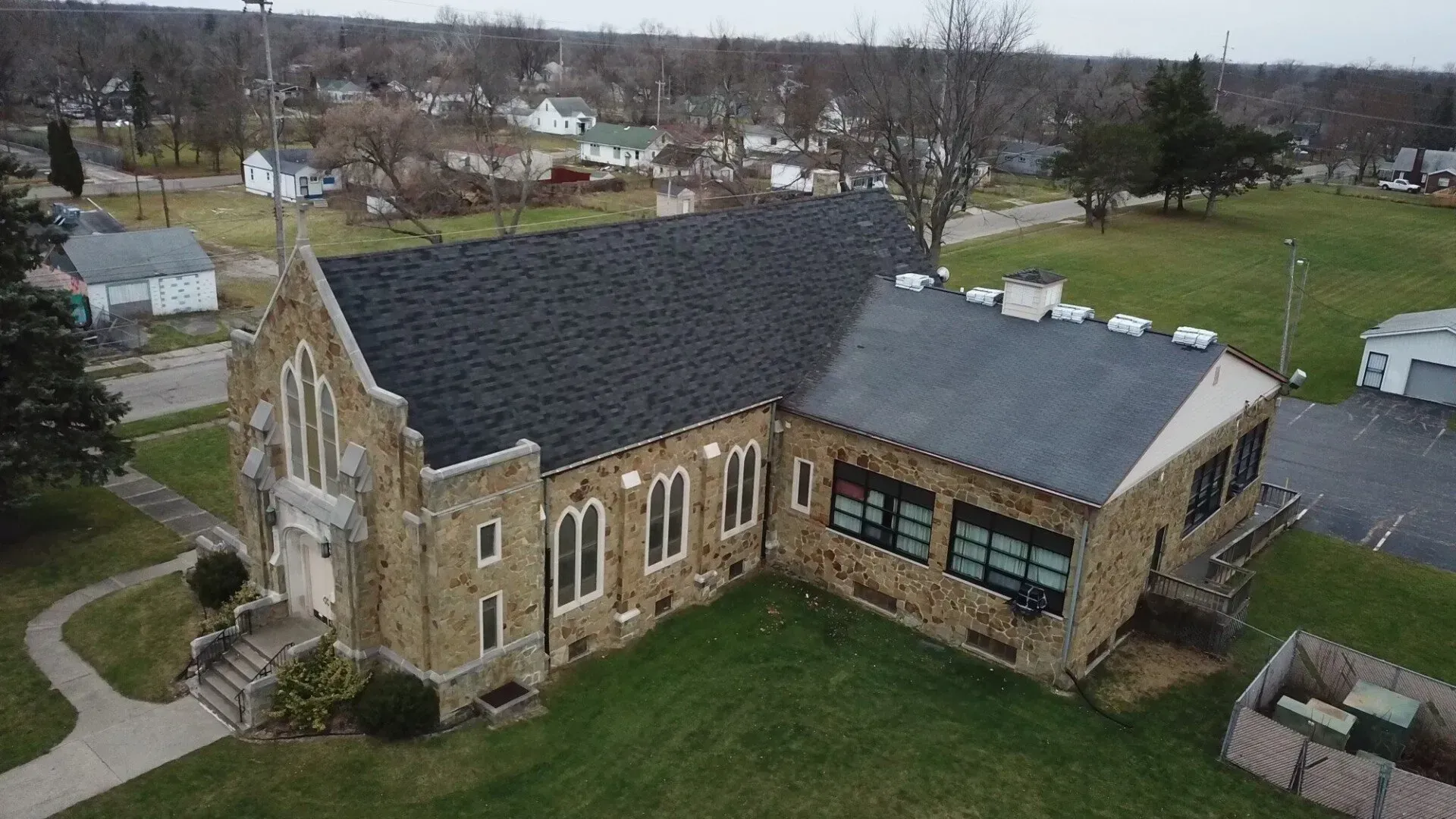 An aerial view of a church with a black roof in a small town.
