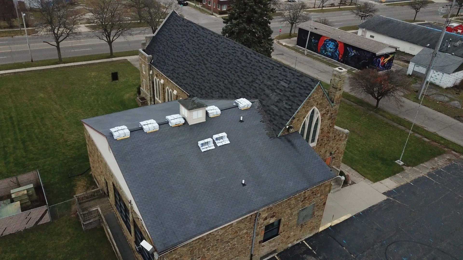 An aerial view of a church with a roof that has solar panels on it.