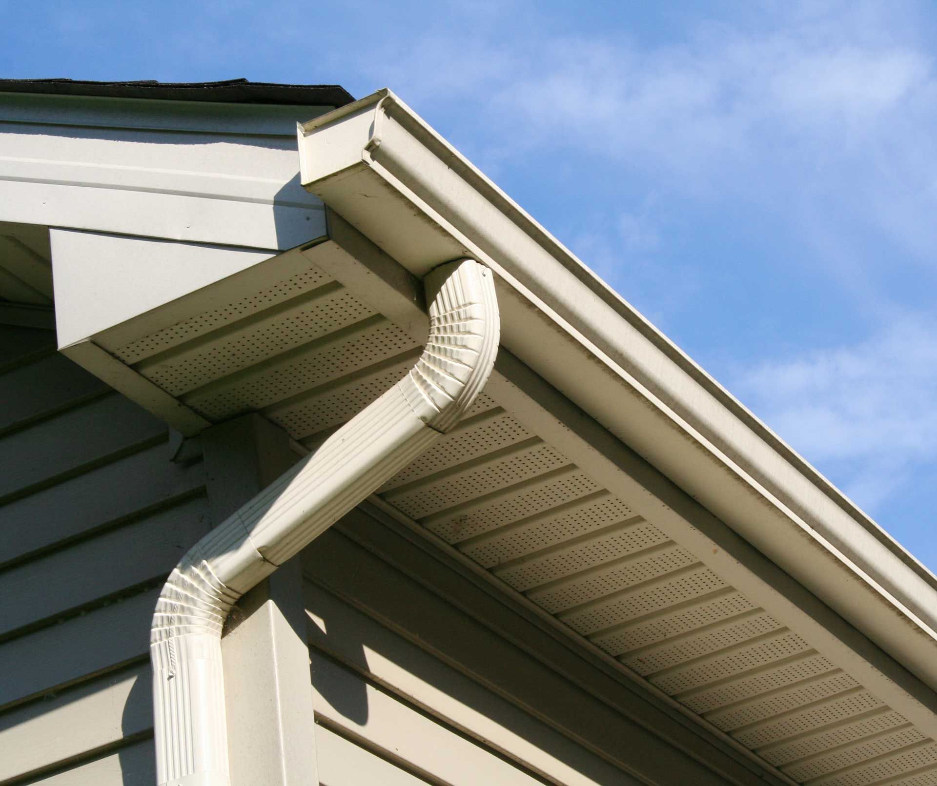 A gutter on the side of a house with a blue sky in the background