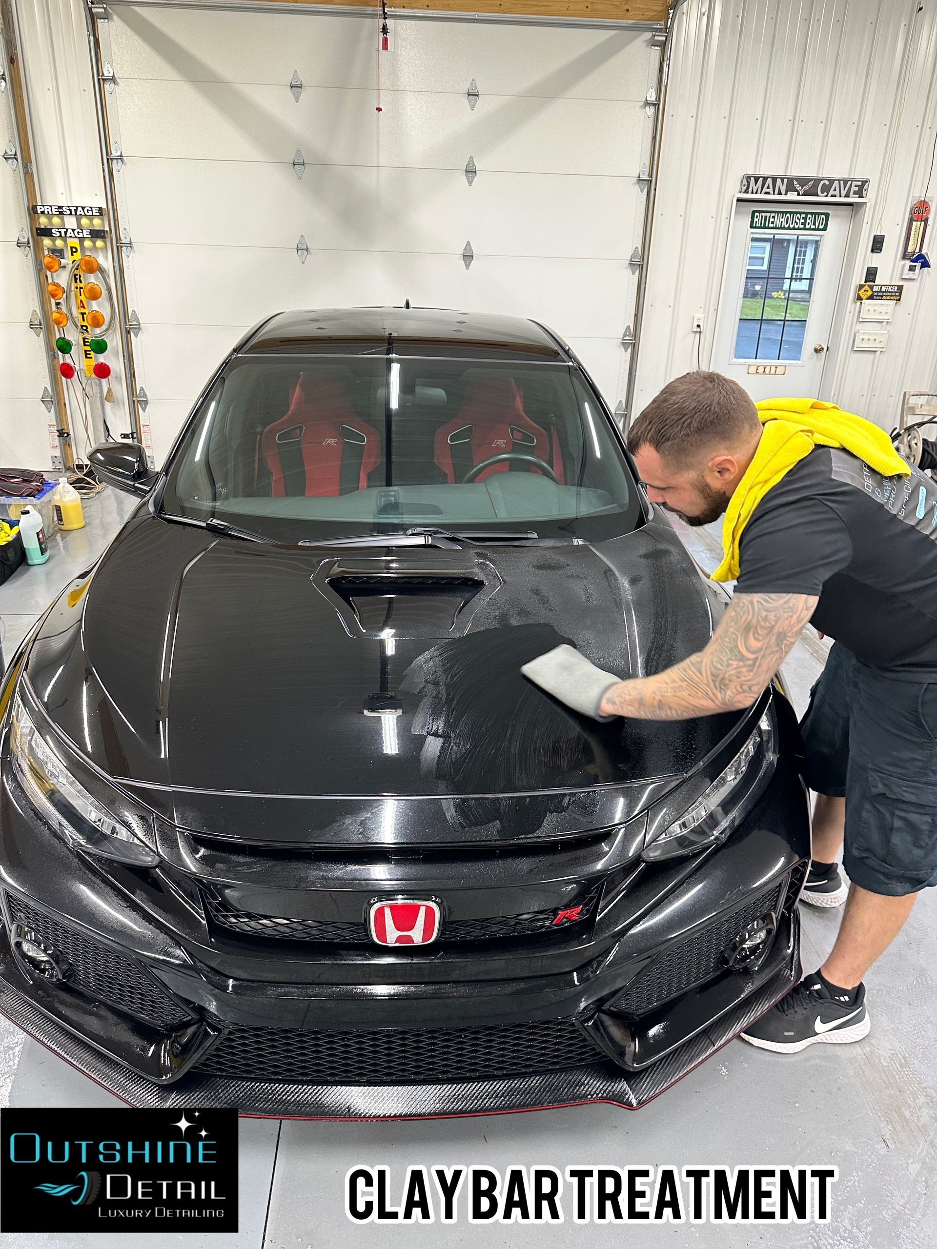 A man is cleaning the hood of a black car with a clay bar treatment.