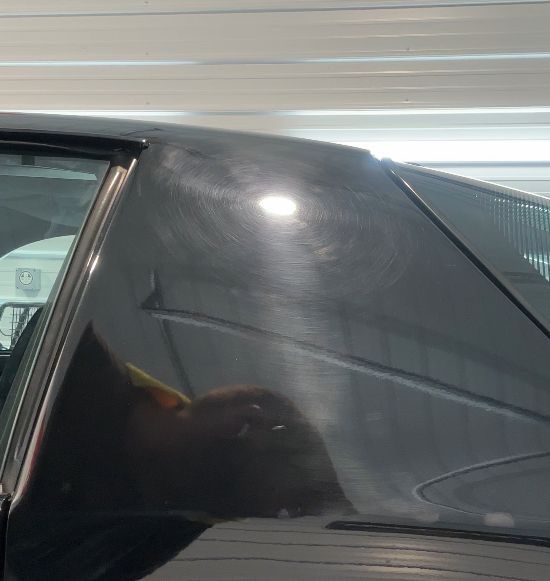 A black car is parked in a garage with the hood open