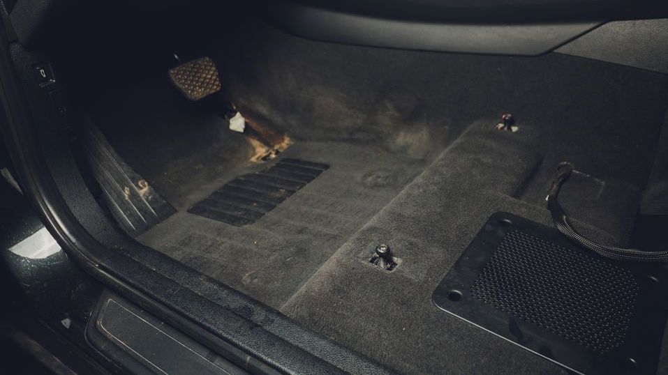 The inside of a car with a carpeted floor and a speaker.