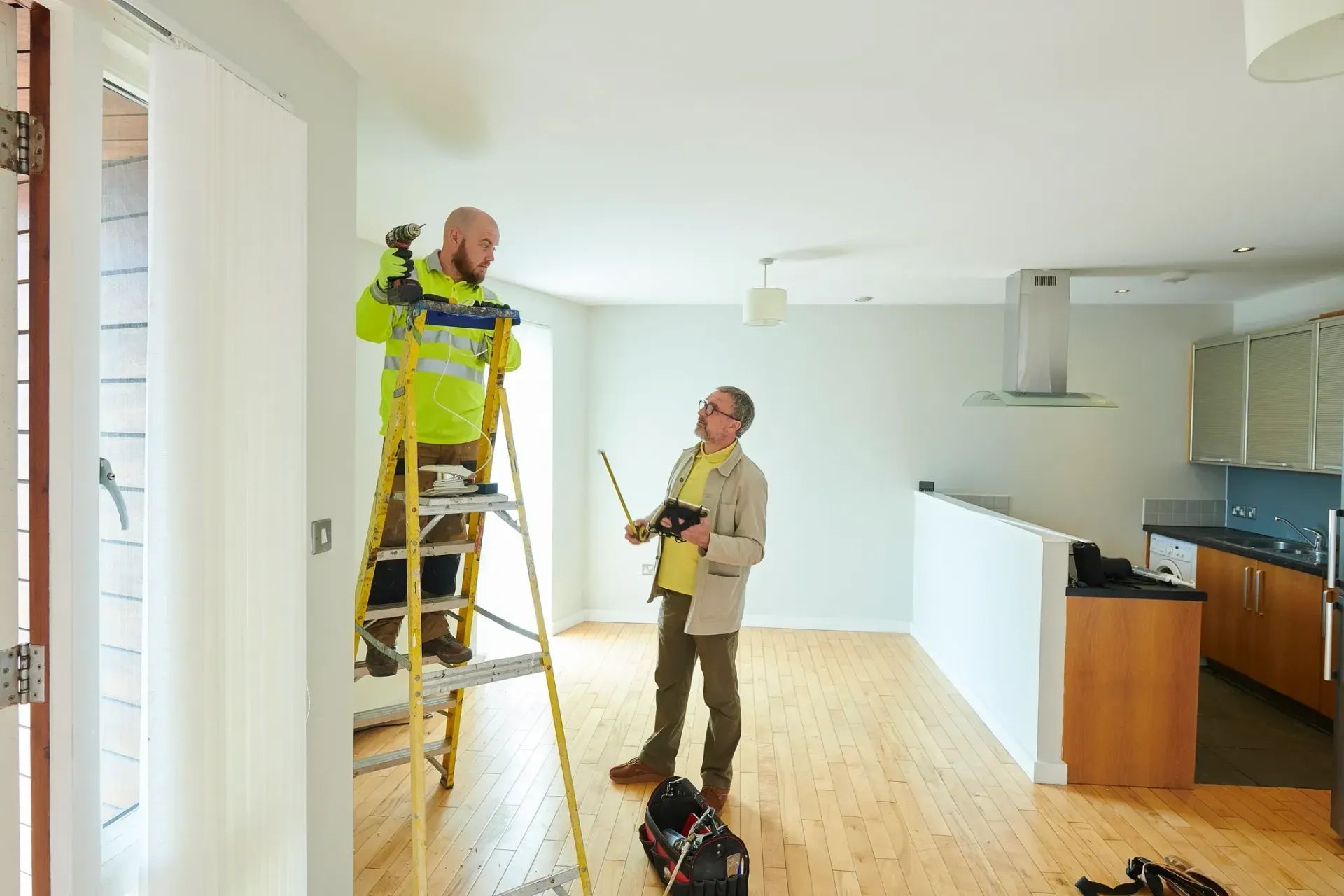 Property maintenance worker on ladder with inspector holding a clipboard