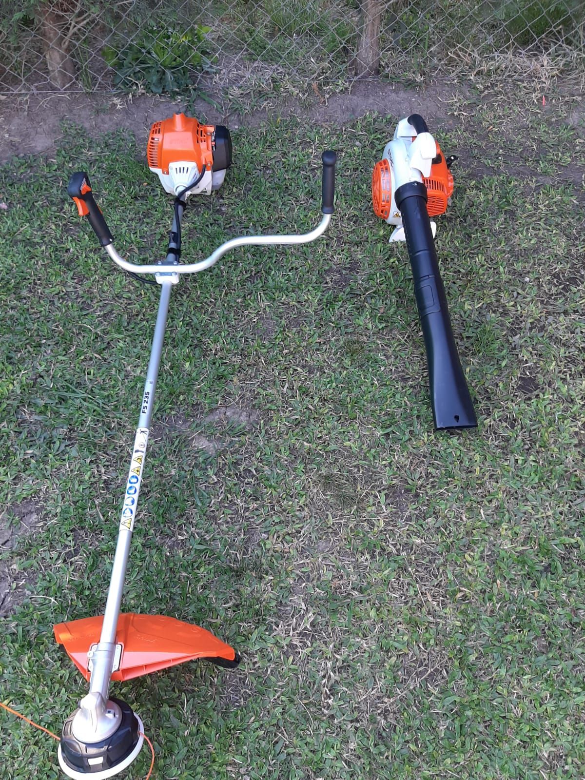 Desbrozadora y soplador de hojas sobre césped. 