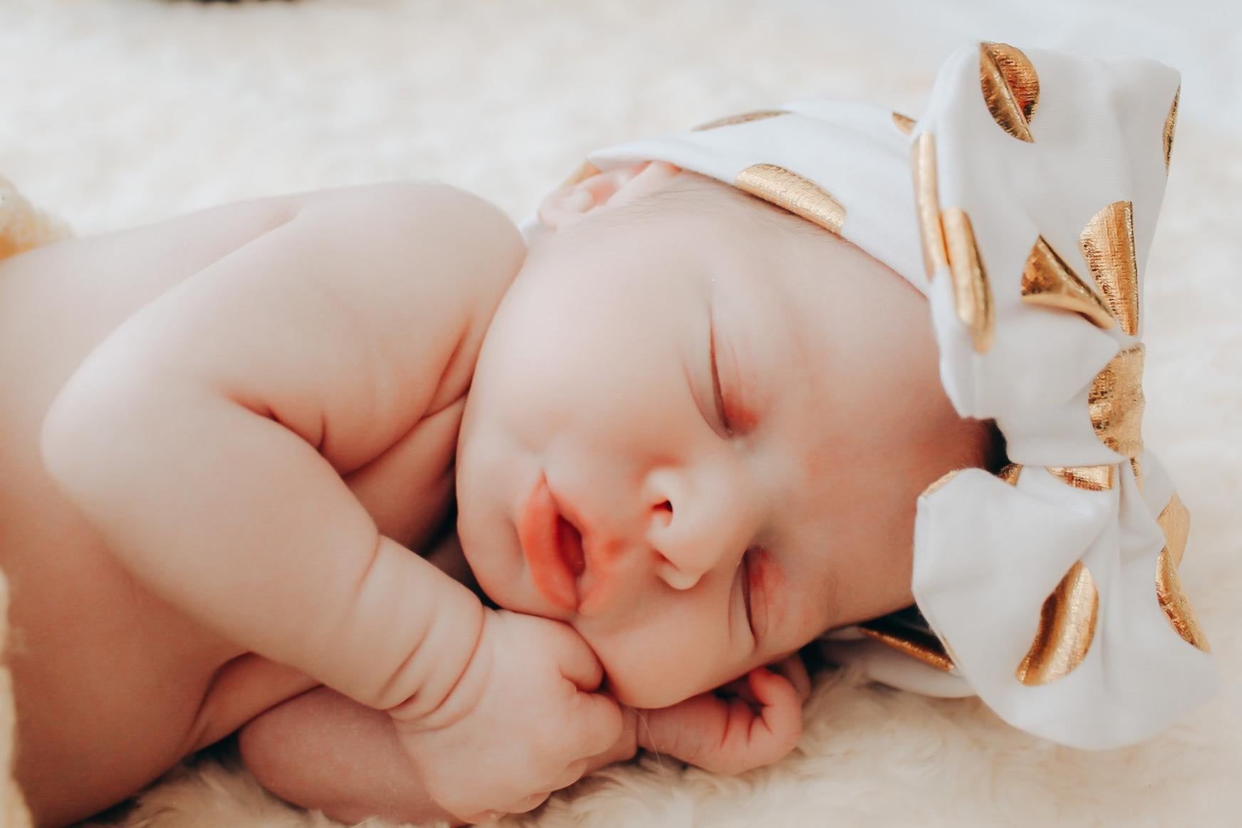 Sleeping newborn baby girl wearing a headband in a newborn portrait photoshoot