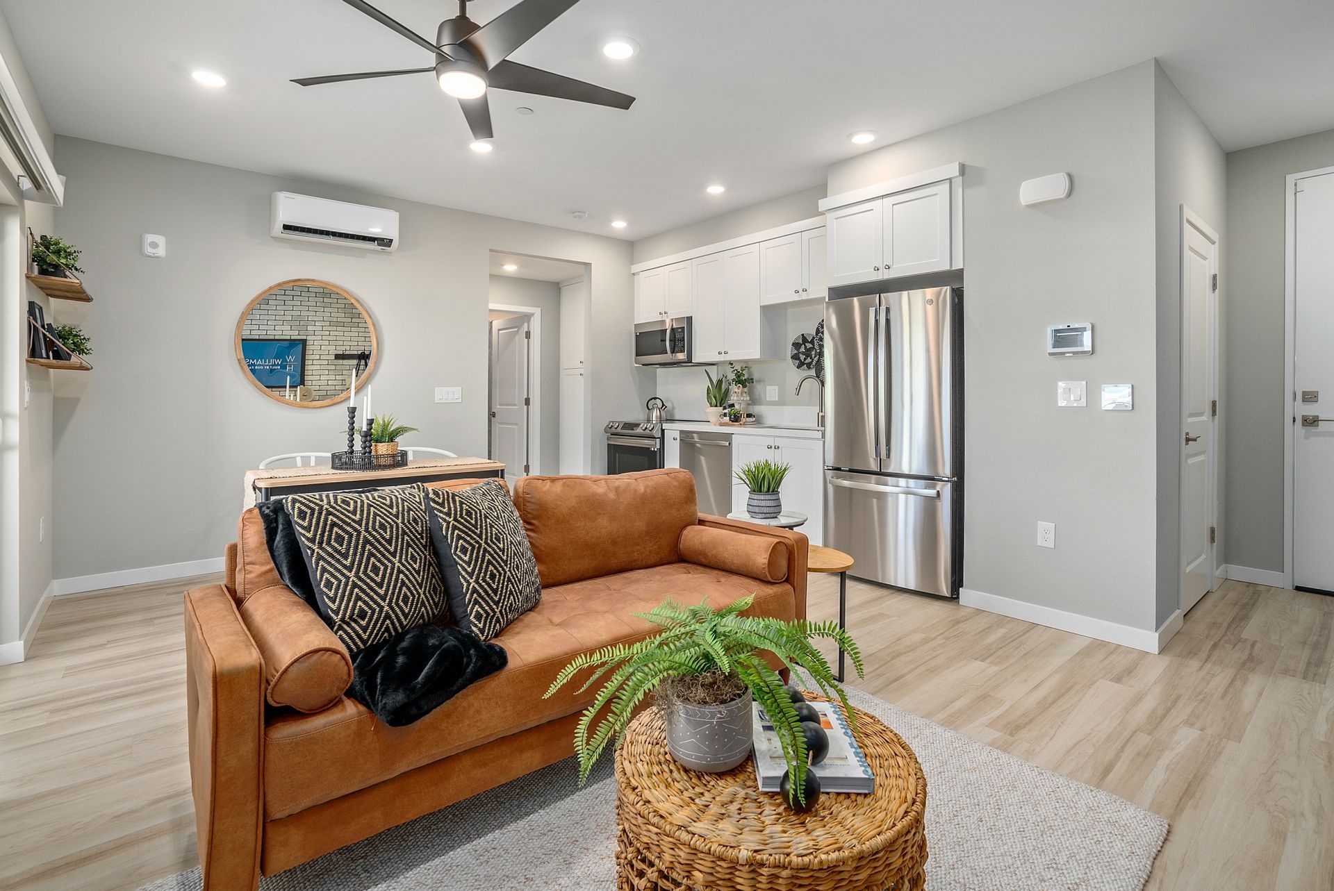 Living room with brown sofa, round coffee table, and open kitchen with stainless steel appliances.