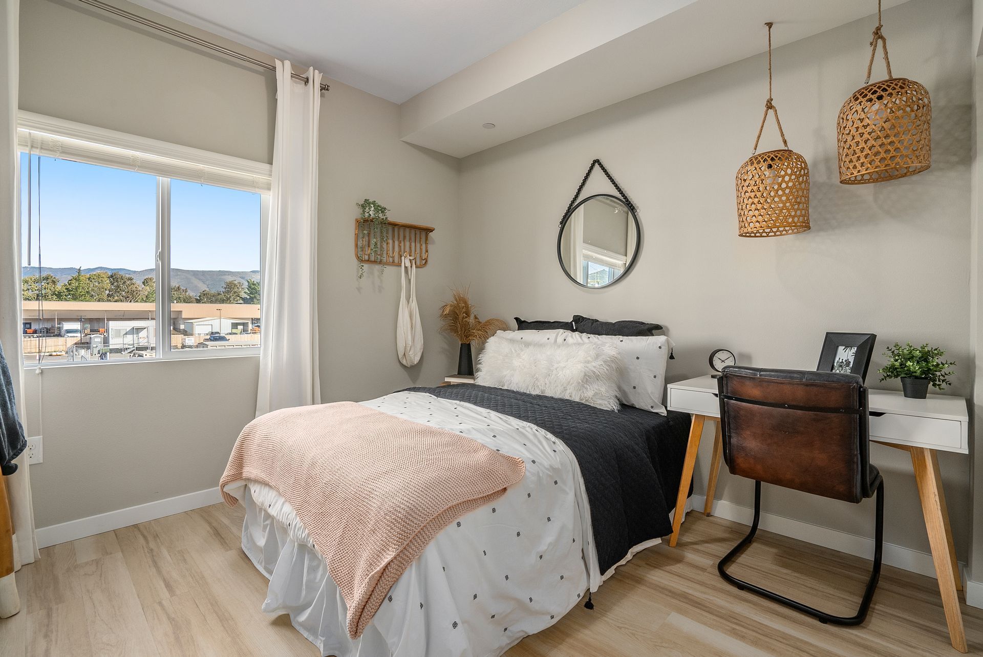 Bedroom with a bed, desk, window, and decorative items. Pale pink, white, and gray color scheme.