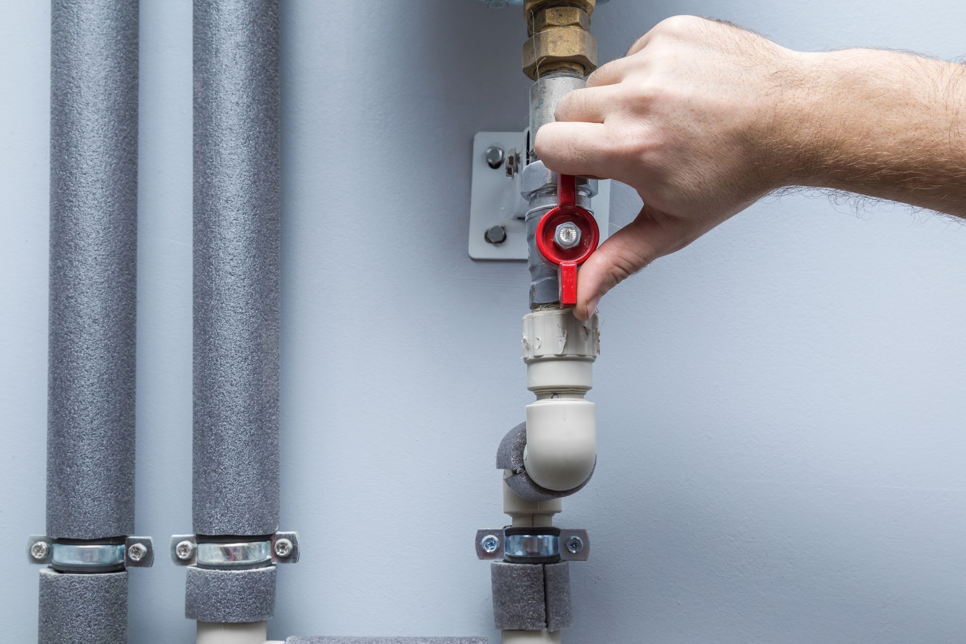 A person is turning a valve on a water pipe.