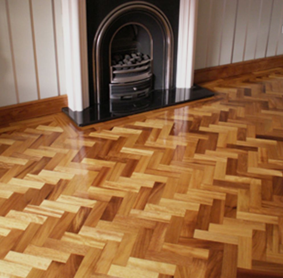 Una lijadora de suelos reposa sobre un suelo de madera marrón claro, recién acabado y brillante