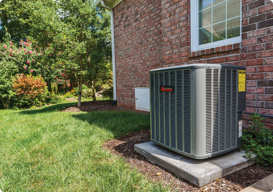 An air conditioner is sitting on the side of a brick house.