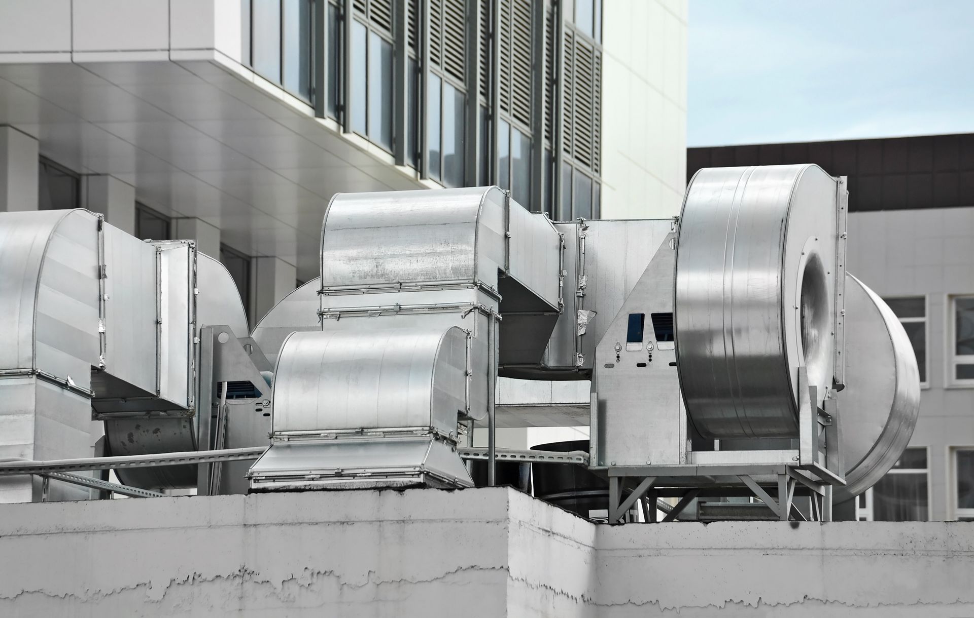 A large stainless steel fan is sitting on top of a building.