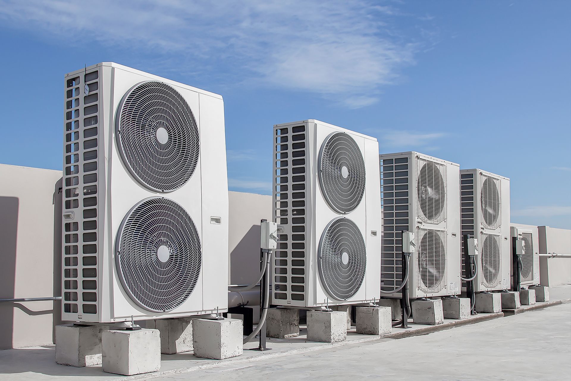 A row of air conditioners are sitting on top of concrete blocks.