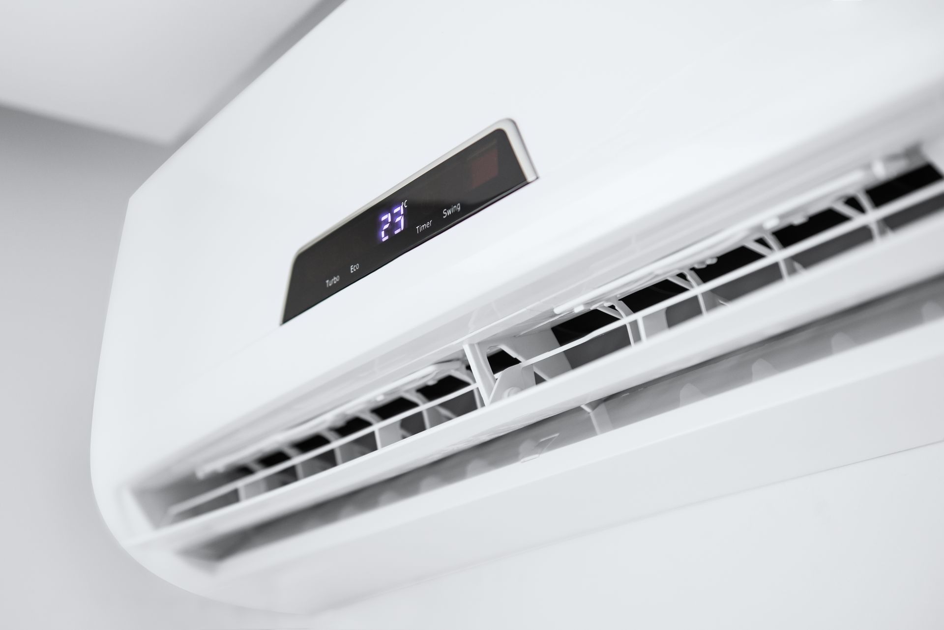 A close up of a white air conditioner hanging on a wall.