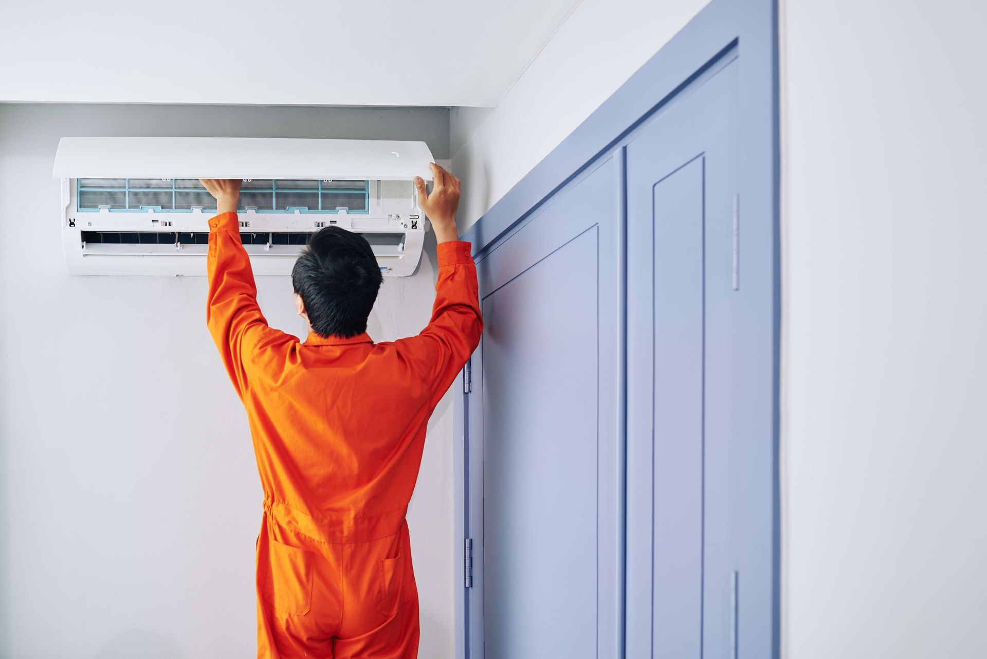 A man is installing an air conditioner in a room.