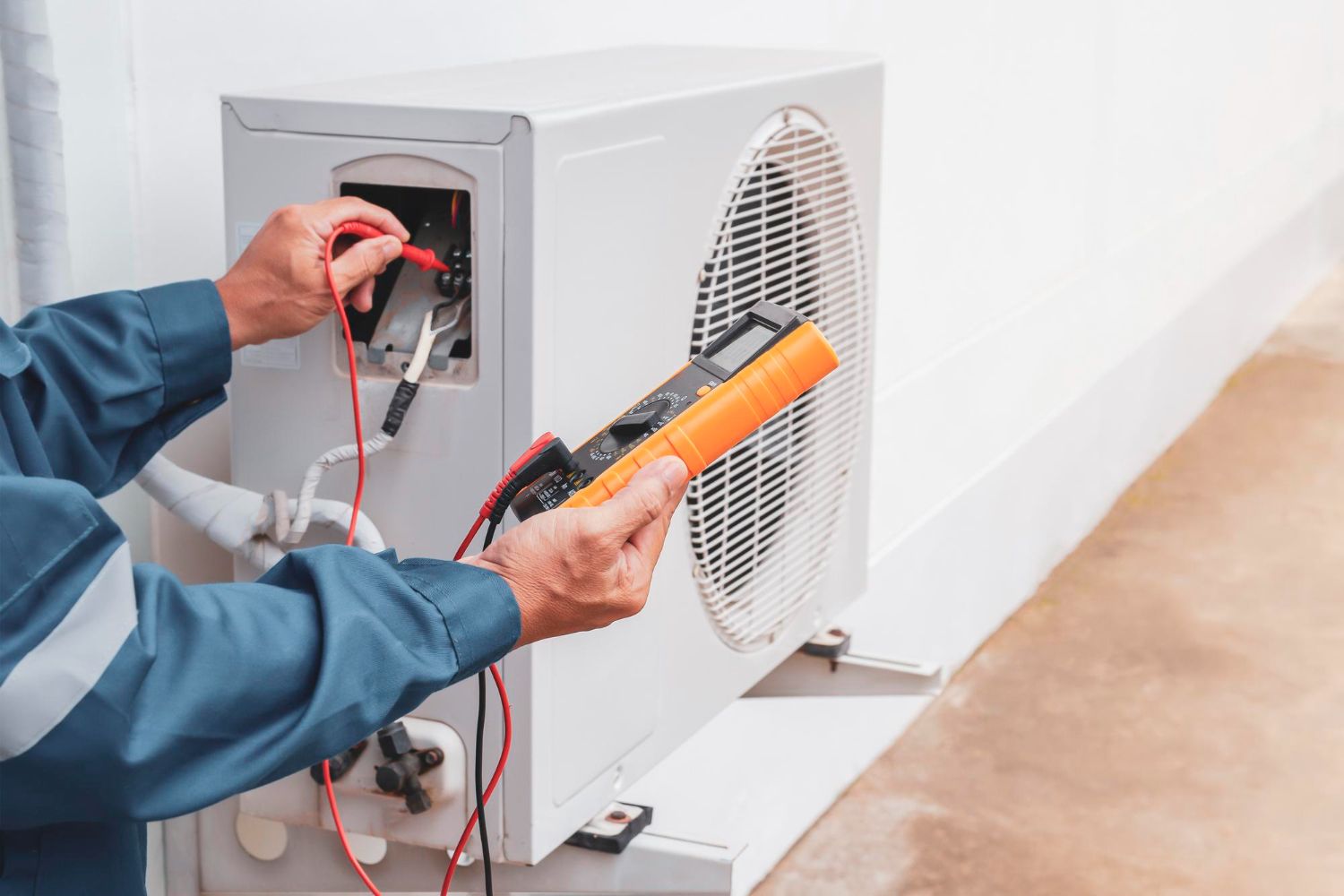 Technician testing an outdoor HVAC unit with a multimeter and probe leads