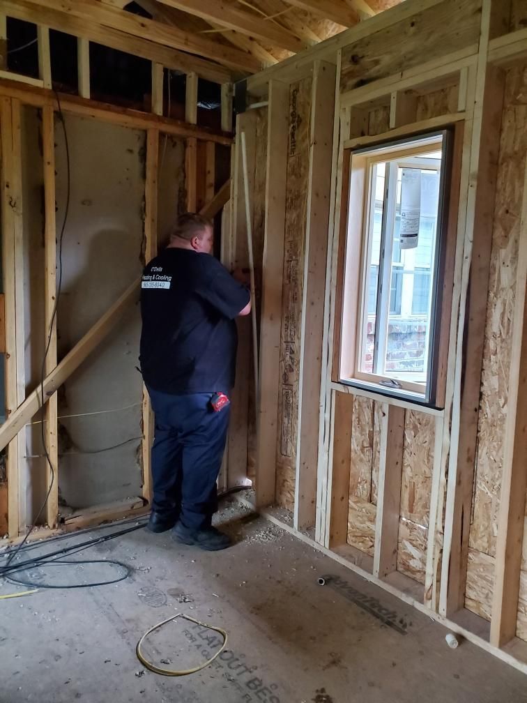 A man is standing in a room with wooden walls and a window.