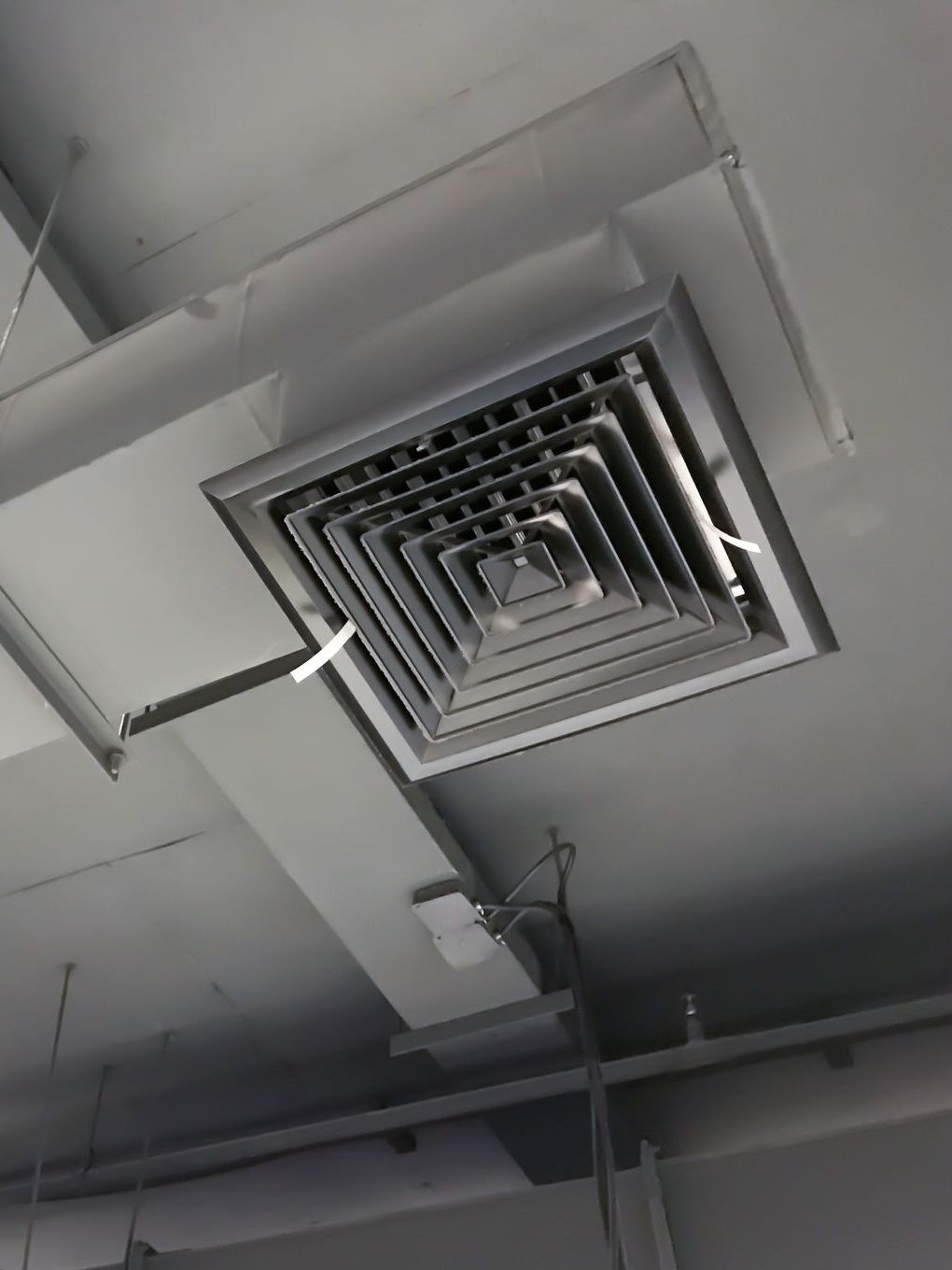 A black and white photo of a ceiling with ducts and vents.