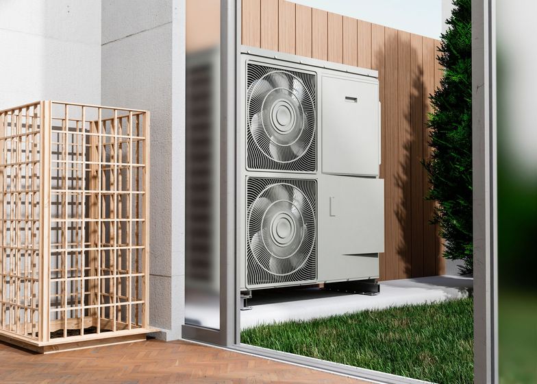 A large air conditioner is sitting on a patio next to a fence.