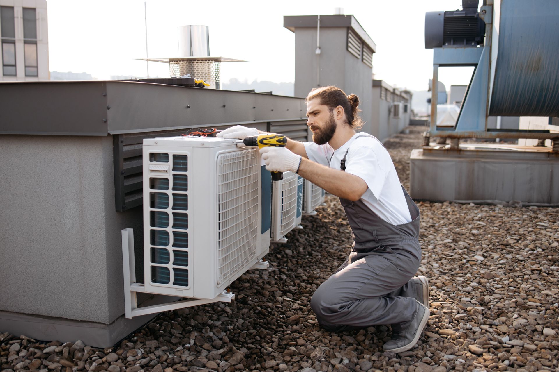 A man is installing an air conditioner on the roof of a building.