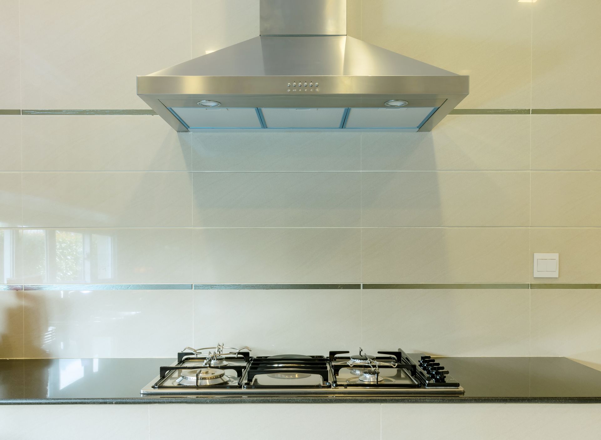 A stove top oven with a hood above it in a kitchen.