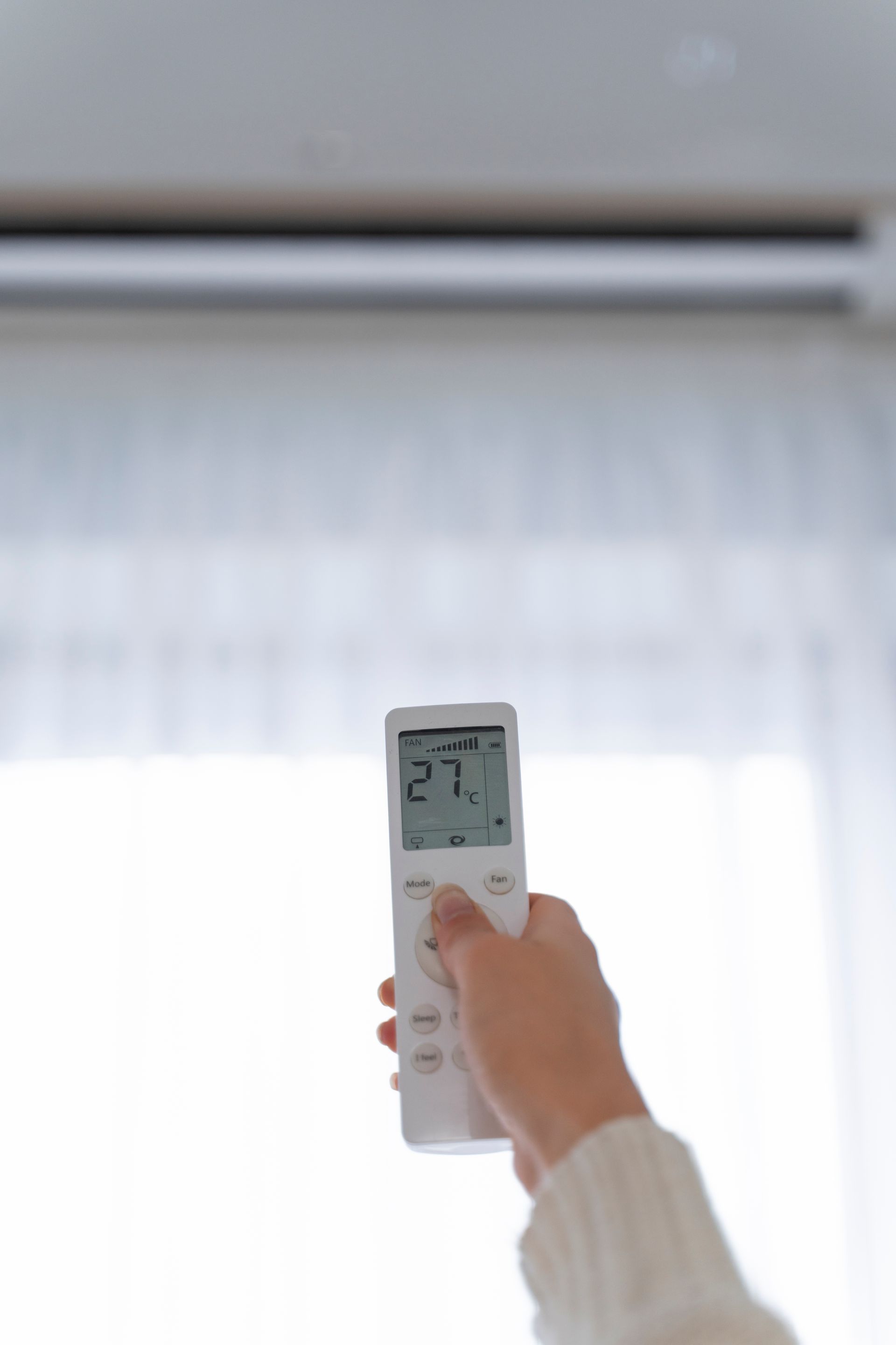 A large air conditioner is sitting on the side of a building next to a window.