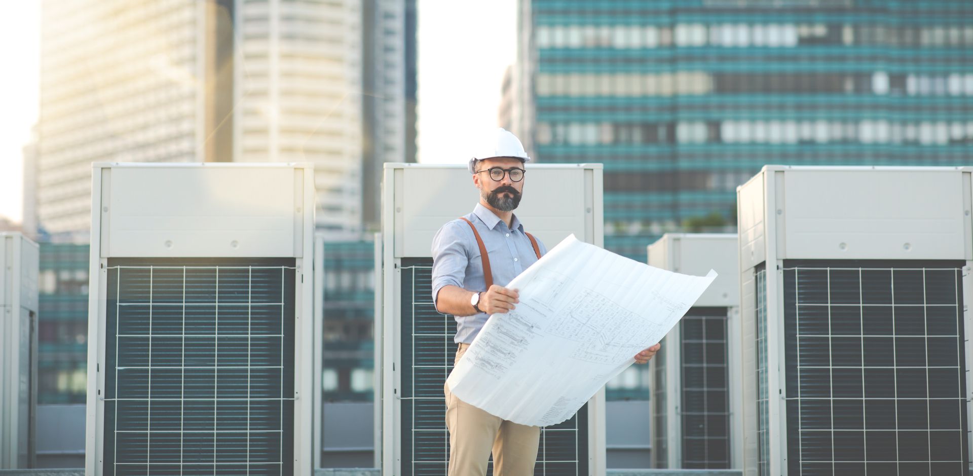 A man is standing on top of a building holding a blueprint.