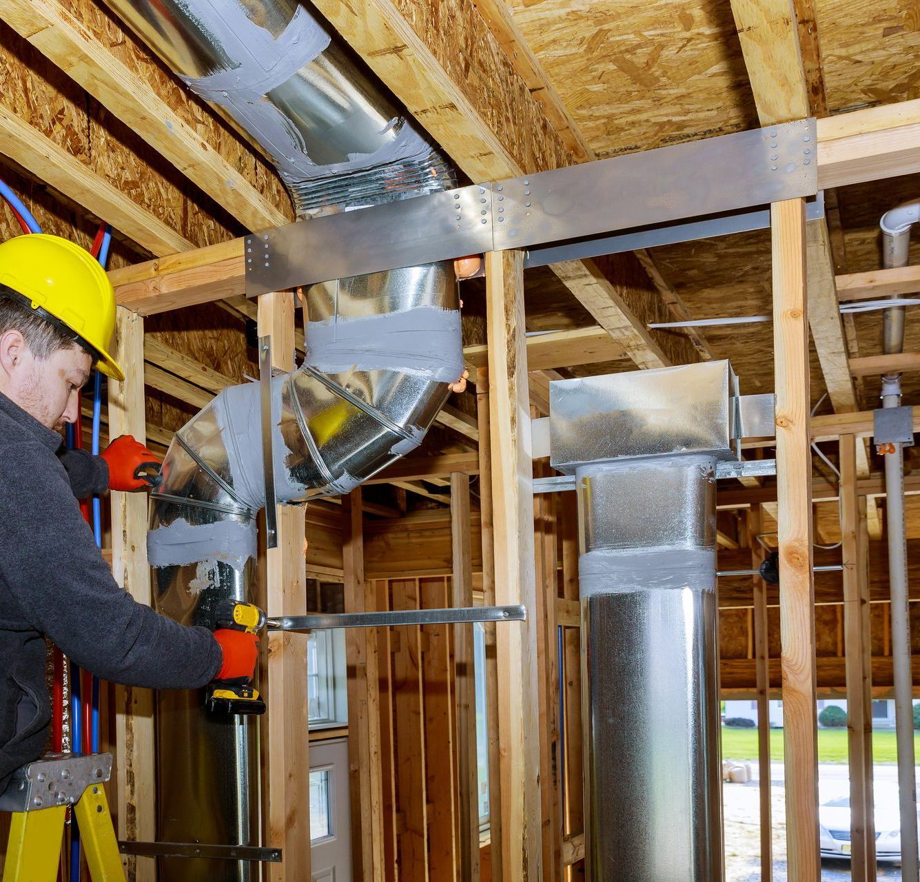 A man wearing a yellow hard hat is working on a metal pipe