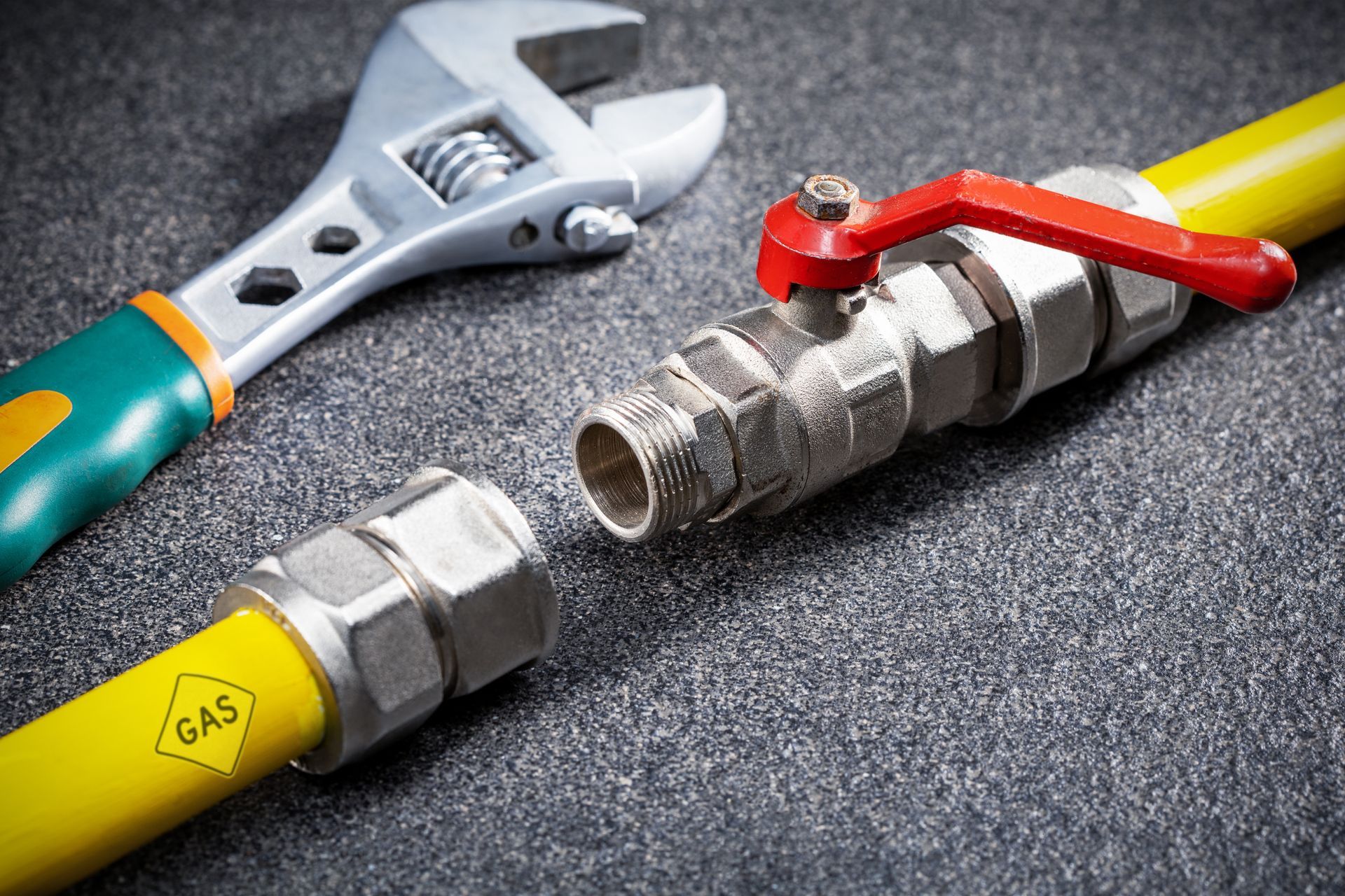 A close up of a gas pipe with a wrench and a valve.