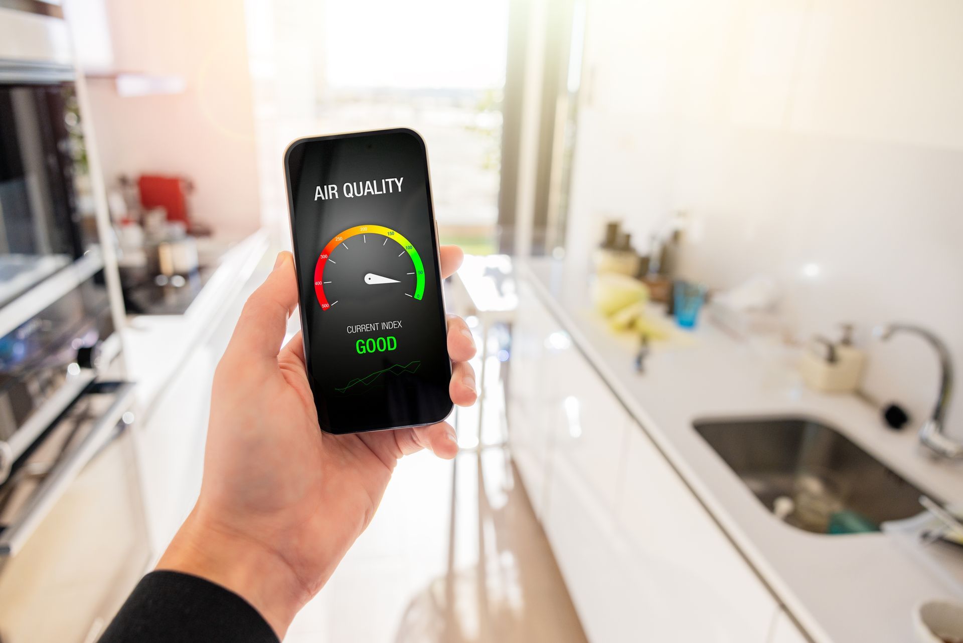 A person is holding a smart phone in their hand in a kitchen.