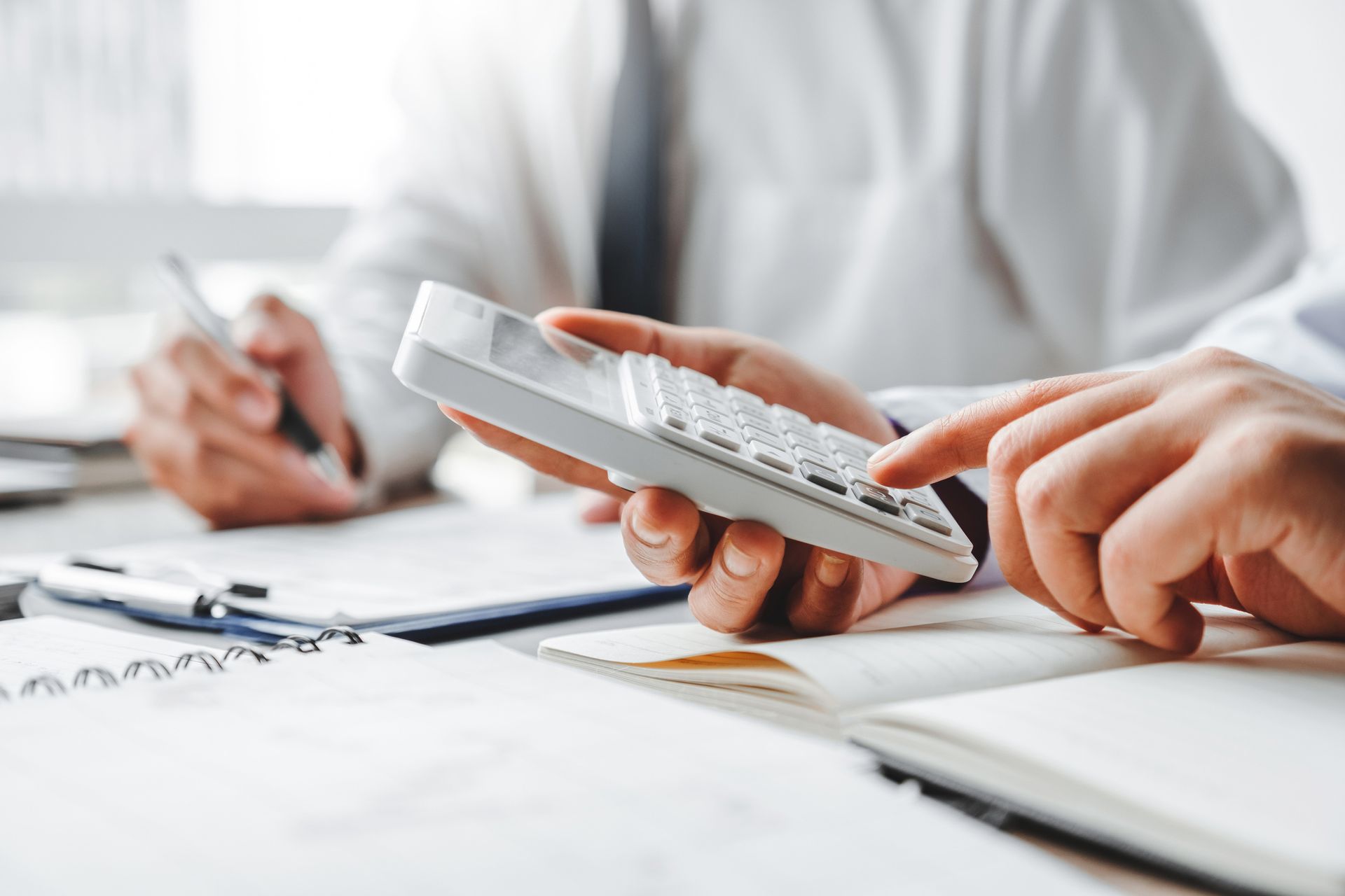 A person is holding a calculator in their hand while sitting at a table.