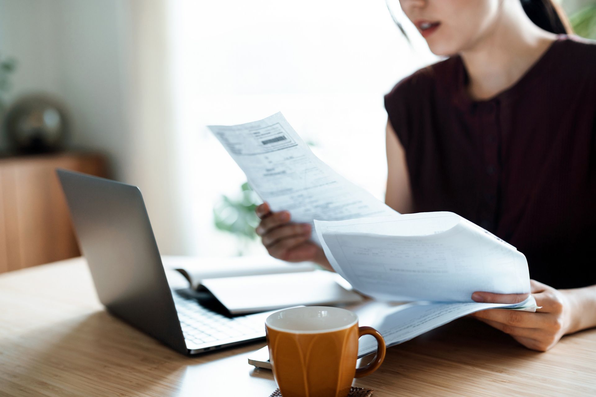 A woman is sitting at a table with a laptop and a cup of coffee.
